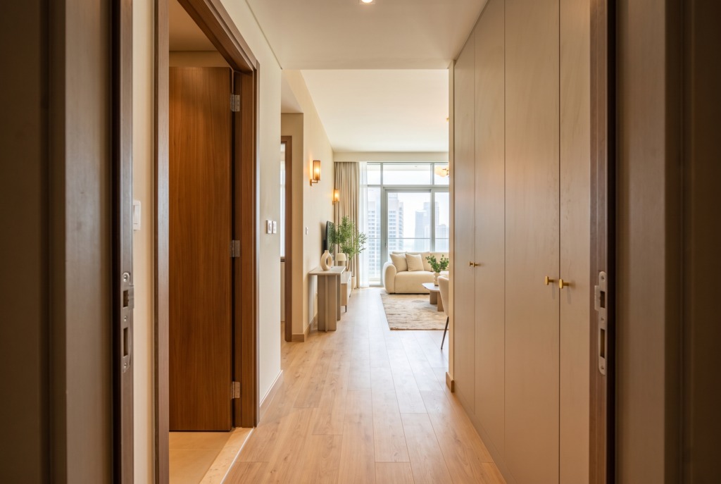 View from the front door into an apartment hallway, with a bedroom door and wardrobes leading to the living area